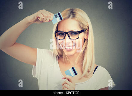 Junge hübsche Frau in Gläser Holding schnitt Hälften der Kreditkarte ein Lächeln auf die Kamera. Stockfoto