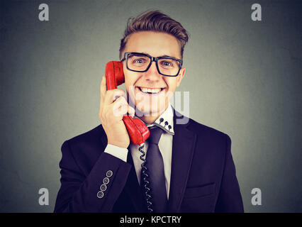 Junge formale Mann in Brillen aufgeregt an der Kamera in das Gespräch auf die alten Telefon suchen. Stockfoto