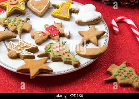 Konzept Bild von Weihnachten Spaß mit Kindern - eine Vielzahl von hausgemachten Lebkuchen auf einer roten Tischdecke in Nahaufnahme. Stockfoto