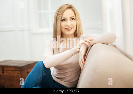Gut aussehende junge Frau auf dem Sofa sitzt. Stockfoto