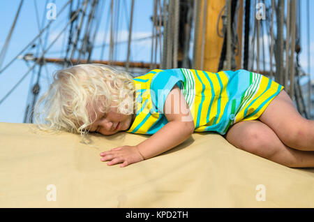 Das kleine Mädchen schlief auf dem Deck eines Segelbootes Stockfoto