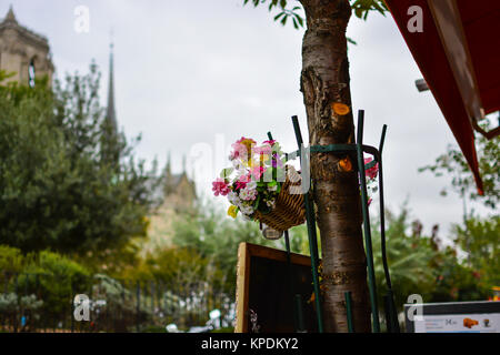Ein Blumengebinde in einem Korb vor einem Cafe in der 4. Arrondissement in Paris Frankreich mit der Kathedrale Notre Dame in der Ferne Stockfoto