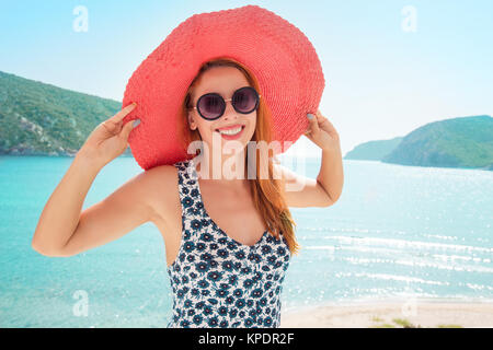 Schöne Inhalt Frau, Sonnenbrille und Hut lächelnd an Kamera auf der Terrasse der Küstenstadt. Stockfoto