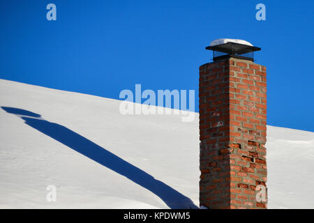 Verfallende rot gemauerten Schornstein auf einem schneebedeckten Dach in Spekulant, NY, USA Stockfoto