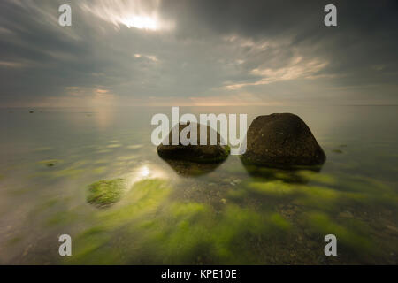 Ostsee mit Algen - Lager mit großen Steinen in der Sonne und lange Belichtung auf den Strand Stockfoto