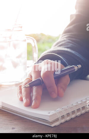 Frau Hand mit Stift schreiben auf Notebook Stockfoto