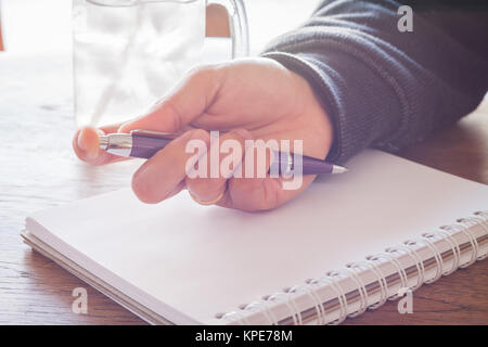 Frau Hand mit Stift schreiben auf Notebook Stockfoto