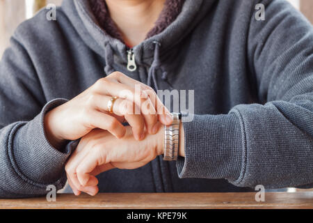 Frau prüft den Zeitpunkt auf eine Armbanduhr Stockfoto