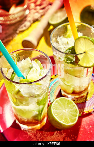 Zwei große klare Gläser gefüllt mit Eis kalt Brasilianische Spezialität von caipirinhas und gekrönt mit Limes und Strohhalme Stockfoto