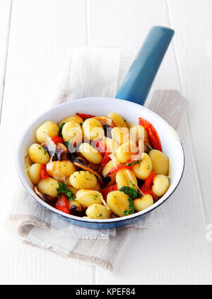 Traditionelle italienische Gnocchi Knödel mit Tomaten und Pilzen gewürzt mit Kräutern gekocht und in einer Pfanne auf weißen Brettern serviert. Stockfoto