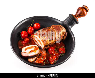 Isoliert von Oben nach Unten Blick auf gefüllte Schweinebraten mit Kirschtomaten in Gusseisen Bratpfanne auf weißem Hintergrund angezeigt. Stockfoto