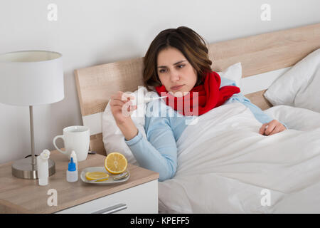 Kranke Frau auf der Suche nach Thermometer Stockfoto