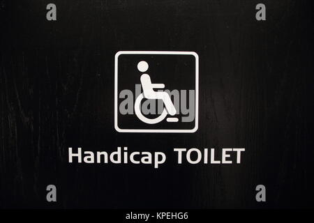 Weiß Handicap behindertengerechte Toilette Zeichen auf schwarzem Holz Stockfoto