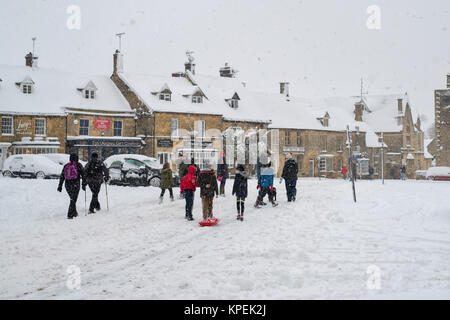 Die Menschen gehen durch den Markt zu Weihnachten im Schnee. Verstauen auf der Wold, Cotswolds, Gloucestershire, England Stockfoto