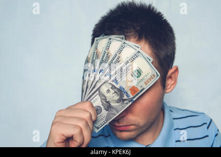 Der Kerl hält eine 500-Dollar Bill vor meinen Augen. durch Geld sehen. versteckt sich hinter Geld. Seine Augen für eine Bestechung. Stockfoto