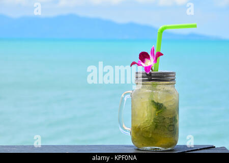 Großes Glas Mojito mit orchideenblüte am Strand Stockfoto