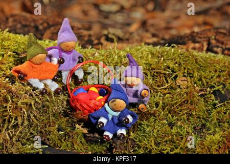 Vier kleine Zwerge mit Ostereiern und fliegen auf der Nase im Wald Stockfoto