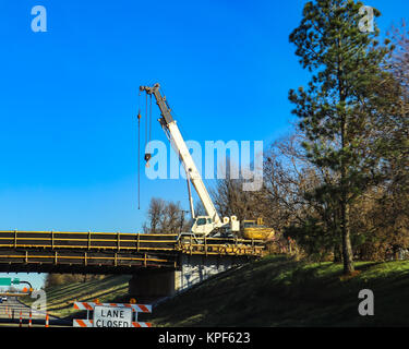 Große weiße mobilen Kran auf Brücke über einem Highway mit Weg von hohen geschlossen Pine Tree und sehr blauen Himmel Stockfoto