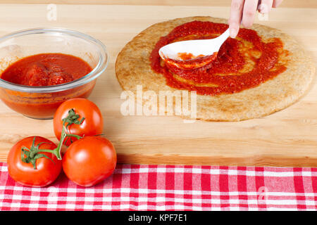 Verbreitung Tomatensauce auf einer Pizza Teig Stockfoto