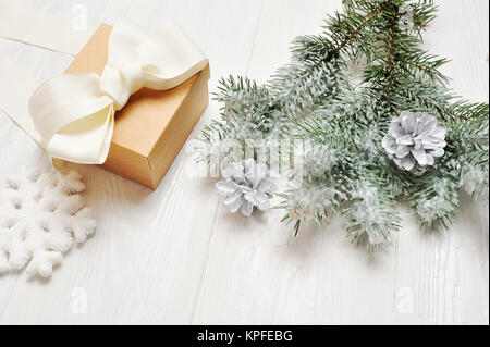 Mockup Weihnachtsgeschenk vintage mit schneebedeckten Zweig der Tannen auf weißem Holz Hintergrund Stockfoto