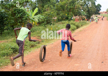 Lugazi, Uganda. 15. Juni 2017. Ugandische Kinder laufen und Spinning Rad Reifen. Stockfoto