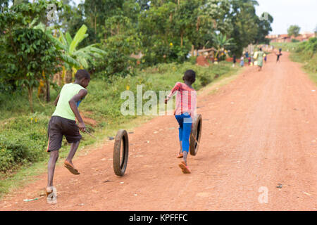 Lugazi, Uganda. 15. Juni 2017. Ugandische Kinder laufen und Spinning Rad Reifen. Stockfoto