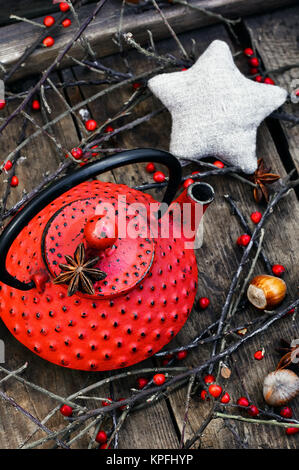 Rot Metall Wasserkocher, Zweige mit Beeren auf hölzernen Hintergrund Stockfoto