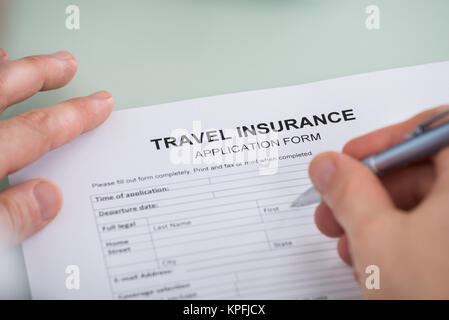Person mit der Hand über Reiseversicherung Antragsformular Stockfoto