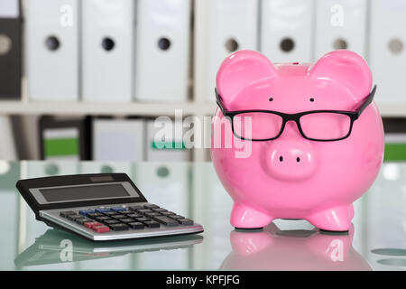 Sparschwein tragen Brillen und Rechner auf dem Schreibtisch Stockfoto