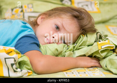 Mädchen auf dem Bett liegend und nach rechts schauend Stockfoto