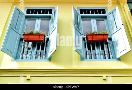 Ein paar antike Fenster mit geöffneten blauen Fensterläden aus Holz und Geländer auf der Vorderseite eines traditionellen Singapur shop Haus im historischen Arab Street. Stockfoto