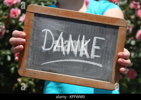DANKE (in deutscher Sprache) mit Kreide auf Schiefer von jungen weiblichen gezeigt geschrieben Stockfoto