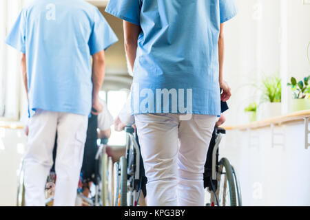 Betreuer push Senioren im Rollstuhl von Altenheim Stockfoto