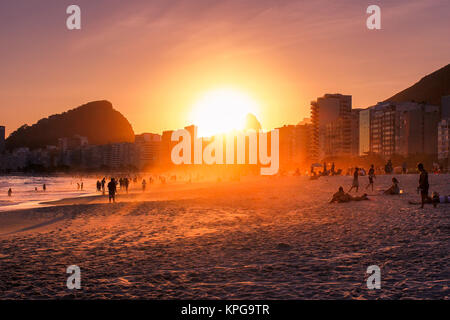 Einen atemberaubenden Sonnenuntergang über eine Gruppe von Menschen an den Strand von Ipanema in Rio de Janeiro, Brasilien Stockfoto