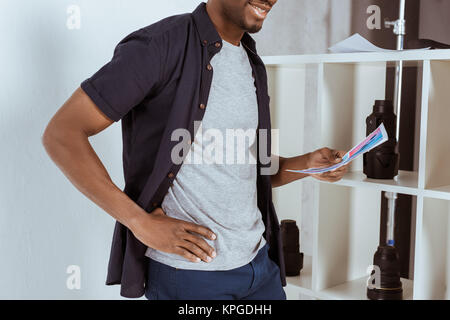7/8 Schuß von lächelnden african american man mit Papieren in der Hand Stockfoto