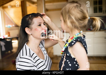 Süße kleine Mädchen zu tun - bis zu Ihren attraktiven Mom mit der Bürste. Stockfoto