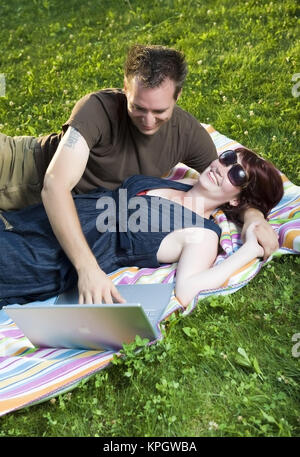 Model Release, Junges Paar so Mit Laptop Auf Einer Decke in der Wiese - paar mit Laptop in der Wiese liegend Stockfoto