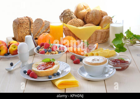 Bunte Frühstück mit Cappuccino, Obst, frischen Orangensaft, Schinken, Käse, frischen Brötchen und Vollkornbrot