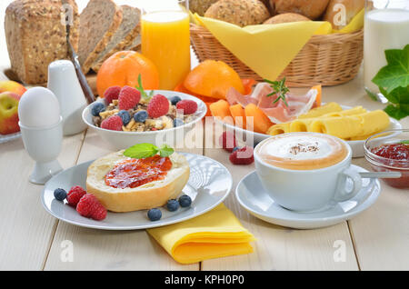 Bunte Frühstück mit Cappuccino, Obst, frischen Orangensaft, Schinken, Käse, frischen Brötchen und Vollkornbrot