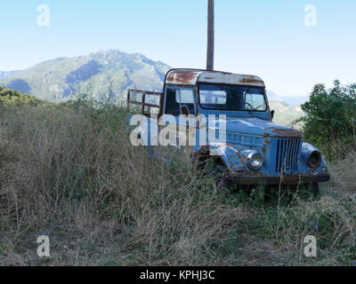 Verlassenes Fahrzeug mit Berge in der Ferne in Griechenland Stockfoto