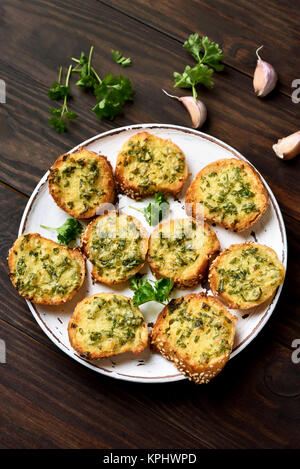 Knoblauch, Käse, Brot mit grünen Kräutern auf Platte über Holz- Hintergrund Stockfoto