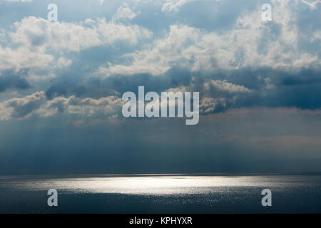 Ostsee im Sommer mit Sonne im Gegenlicht und Reflectionen, Untergehende Sonne bestrahlt Äste und Steine im Meerwasser Stockfoto