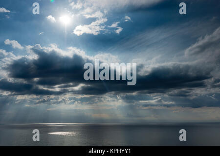 Ostsee im Sommer mit Sonne im Gegenlicht und Reflectionen, Untergehende Sonne bestrahlt Äste und Steine im Meerwasser Stockfoto