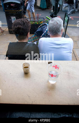 Rückansicht eines älteren Paares außerhalb ein Cafe mit zwei Tassen auf der Fensterbank sitzen Stockfoto