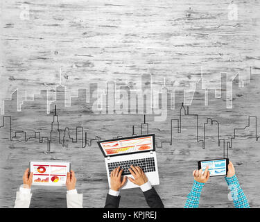 Gruppe von drei Personen mit Geräten in Händen arbeiten zusammen als Symbol der Vernetzung und Kommunikation Stockfoto