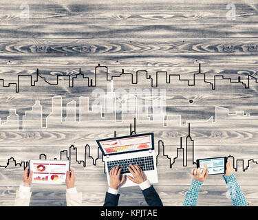 Gruppe von drei Personen mit Geräten in Händen arbeiten zusammen als Symbol der Vernetzung und Kommunikation Stockfoto