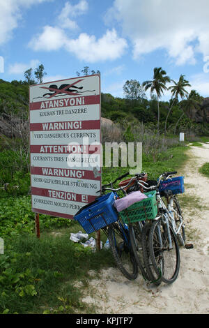Fahrräder und starke aktuelle Warnung unterzeichnen in der Nähe von Wald, La Digue Island, Seychellen. Stockfoto