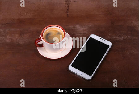 Kaffeetasse und Smartphone auf Holztisch. Ansicht von oben Stockfoto