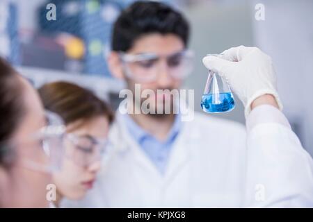 Laboranten an chemischen Flasche mit blauer Flüssigkeit. Stockfoto