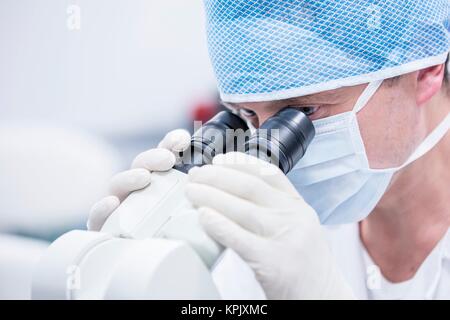Männliche Wissenschaftler Tragen schützender Maske mit Mikroskop. Stockfoto